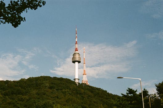 Iconic Namsan Seoul Tower under a clear blue sky captured amid lush greenery.