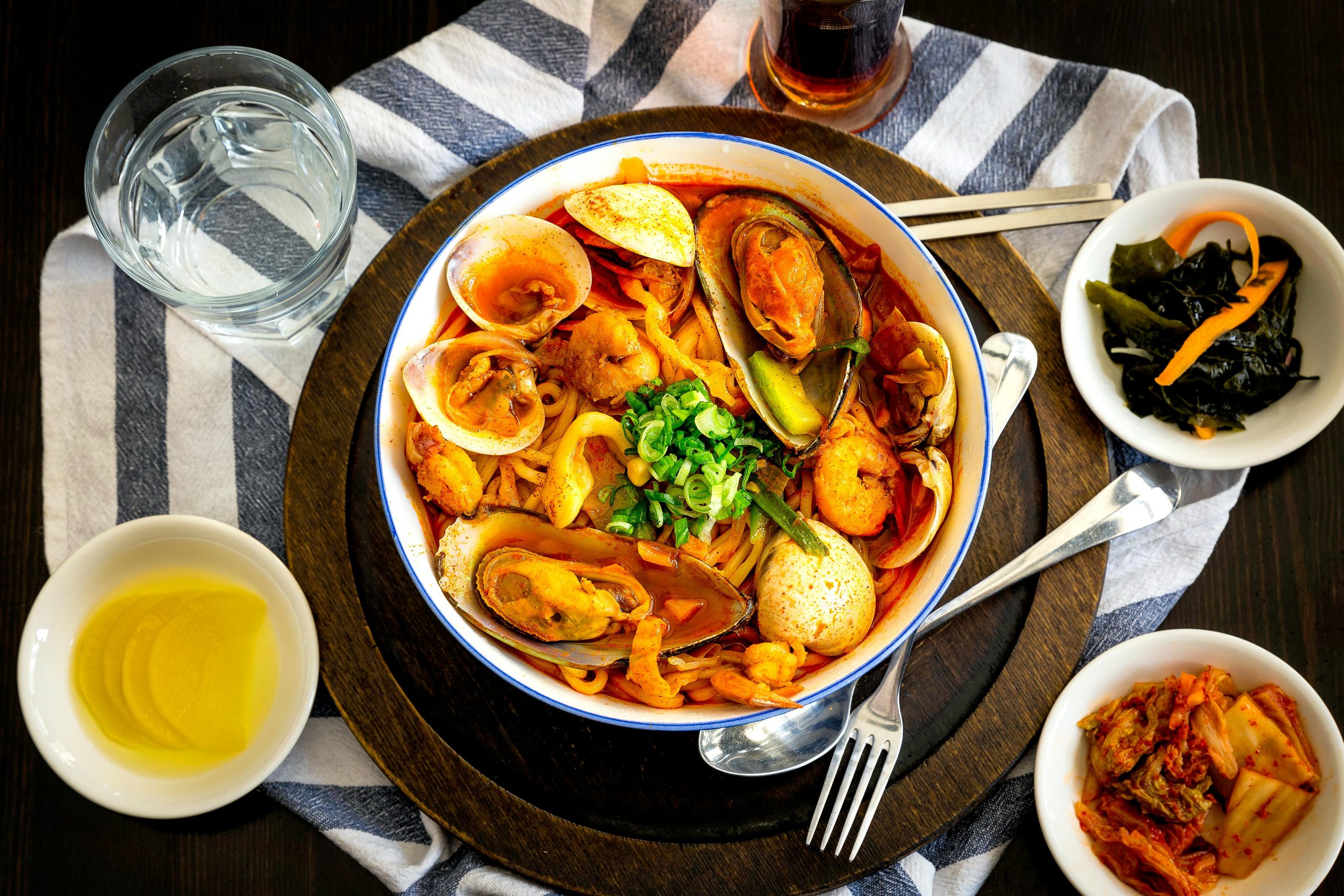 A vibrant Korean seafood noodle dish with side dishes, perfect for a hearty meal.
