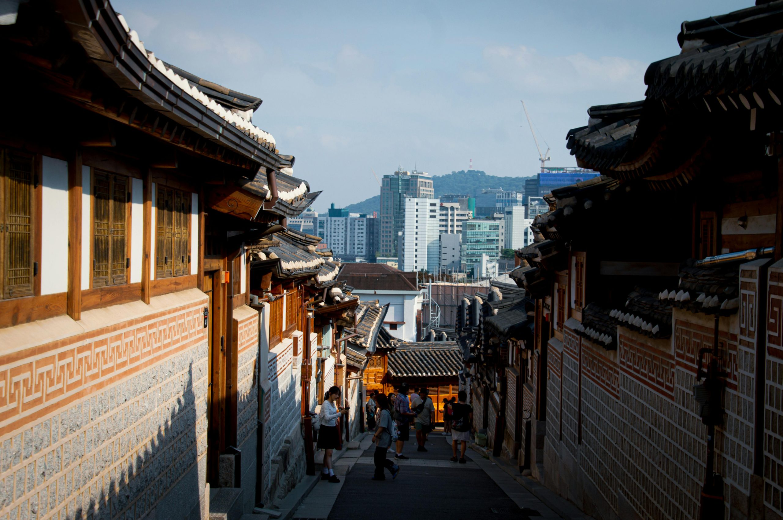 Street view of Bukchon Hanok Village in Seoul, juxtaposing traditional and modern architecture.