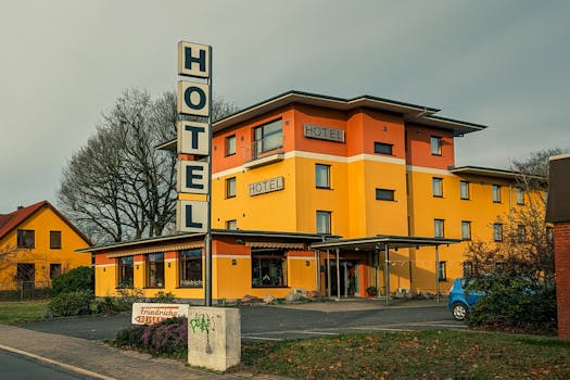 Vibrant yellow hotel exterior with signage under cloudy autumn sky.