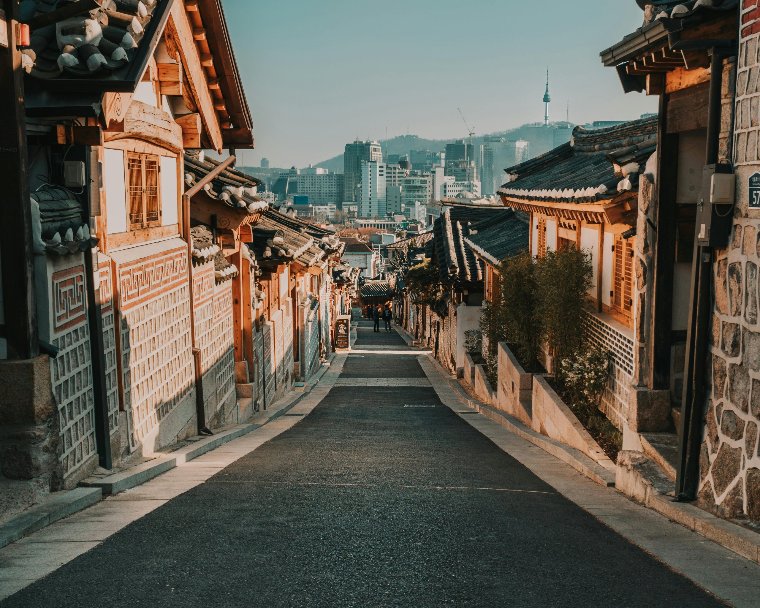 Charming alley in Bukchon Hanok Village showcasing traditional Korean architecture against a modern skyline.