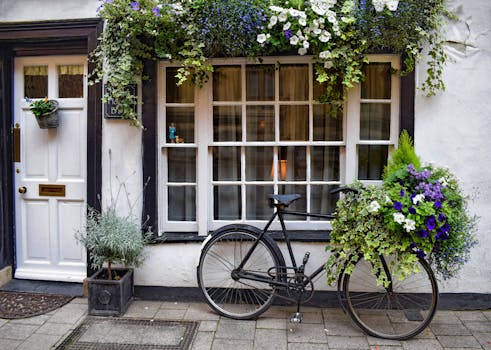 A vintage bicycle adorned with beautiful flowers parked outside a quaint guesthouse window.
